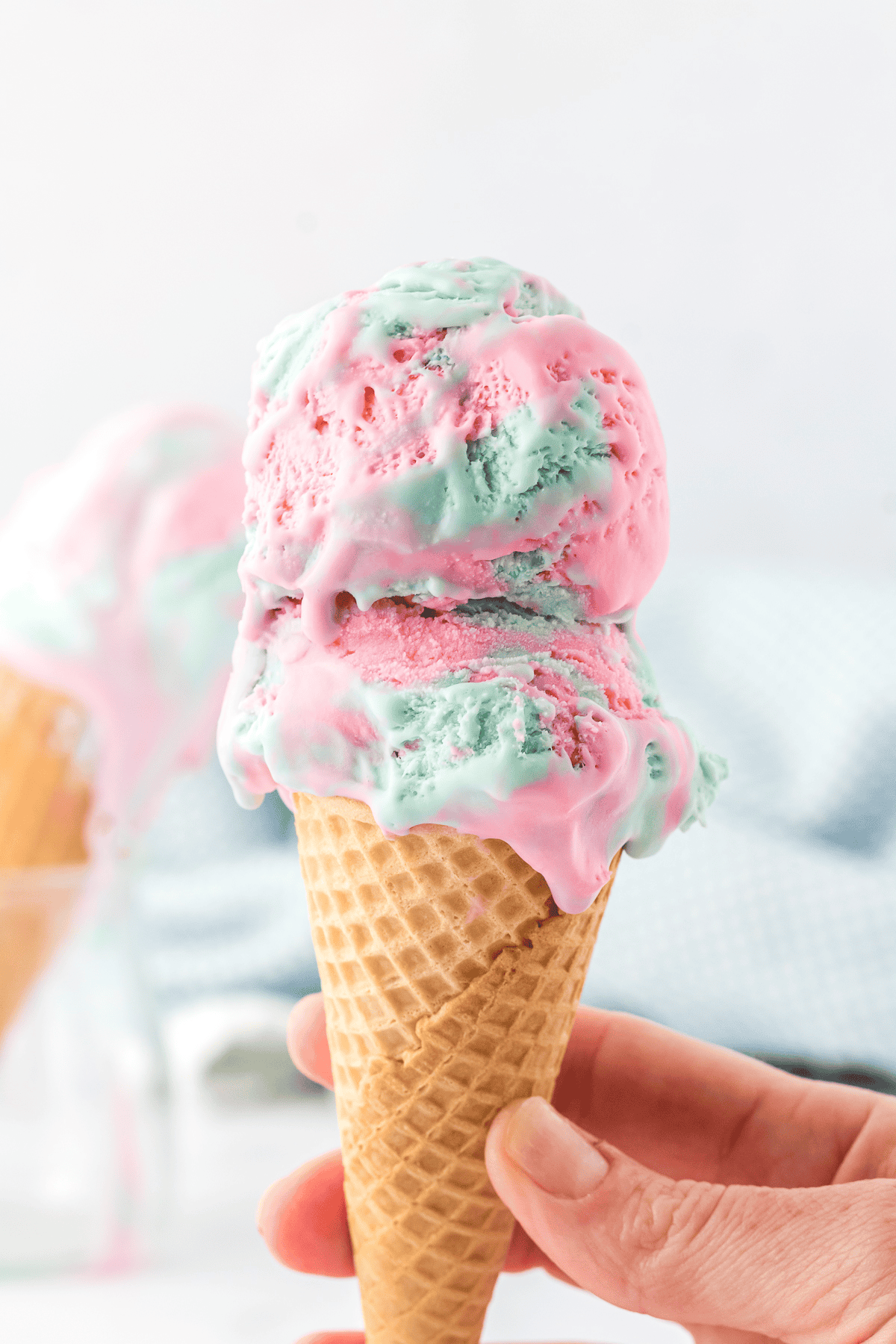 two scoops of cotton candy ice cream in a waffle cone