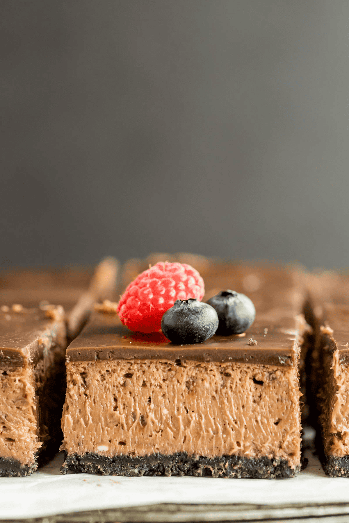 Nutella cheesecake bar on parchment paper and topped with berries