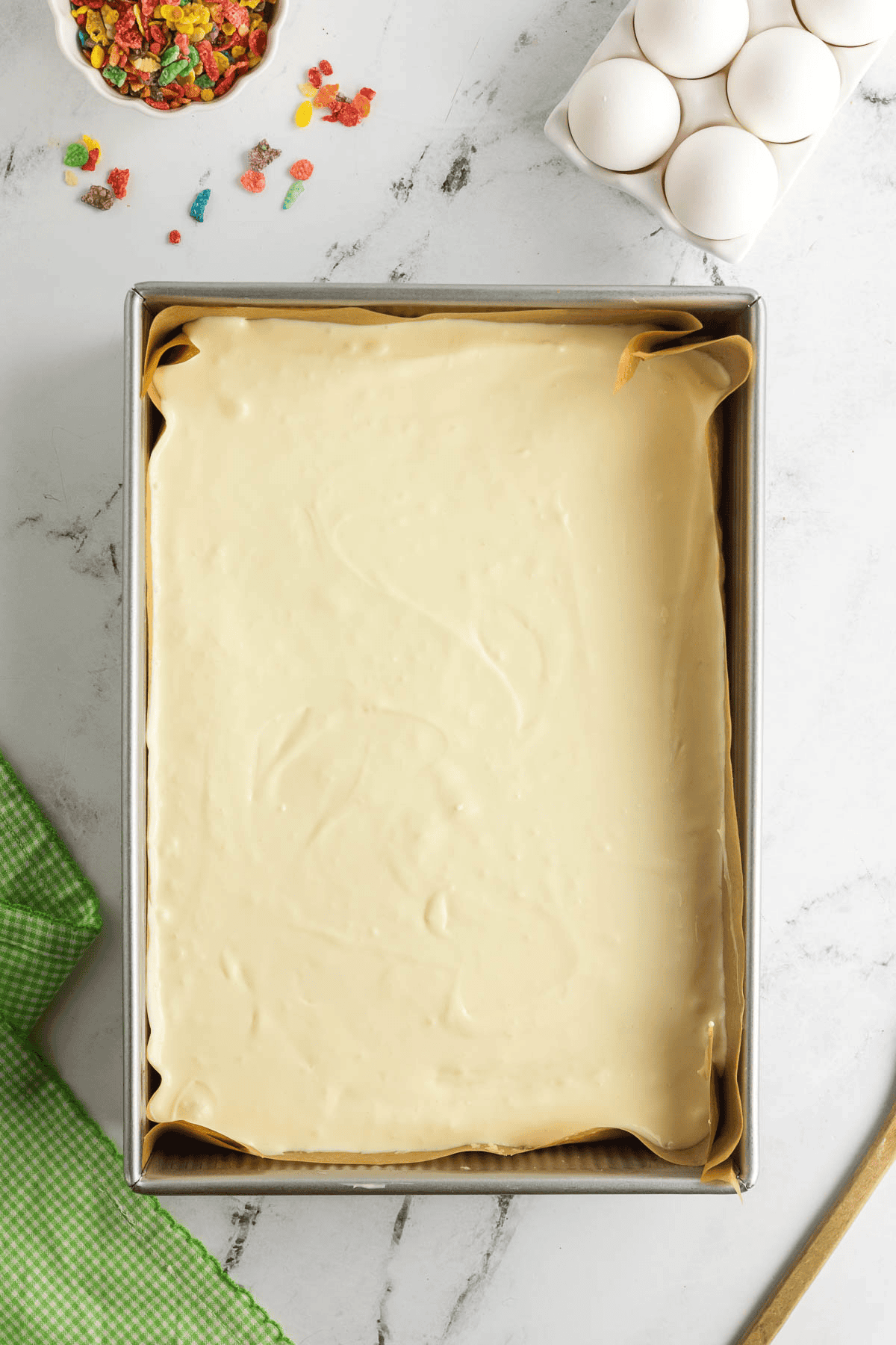 cheesecake batter spread on top of sugar cookie dough in pan