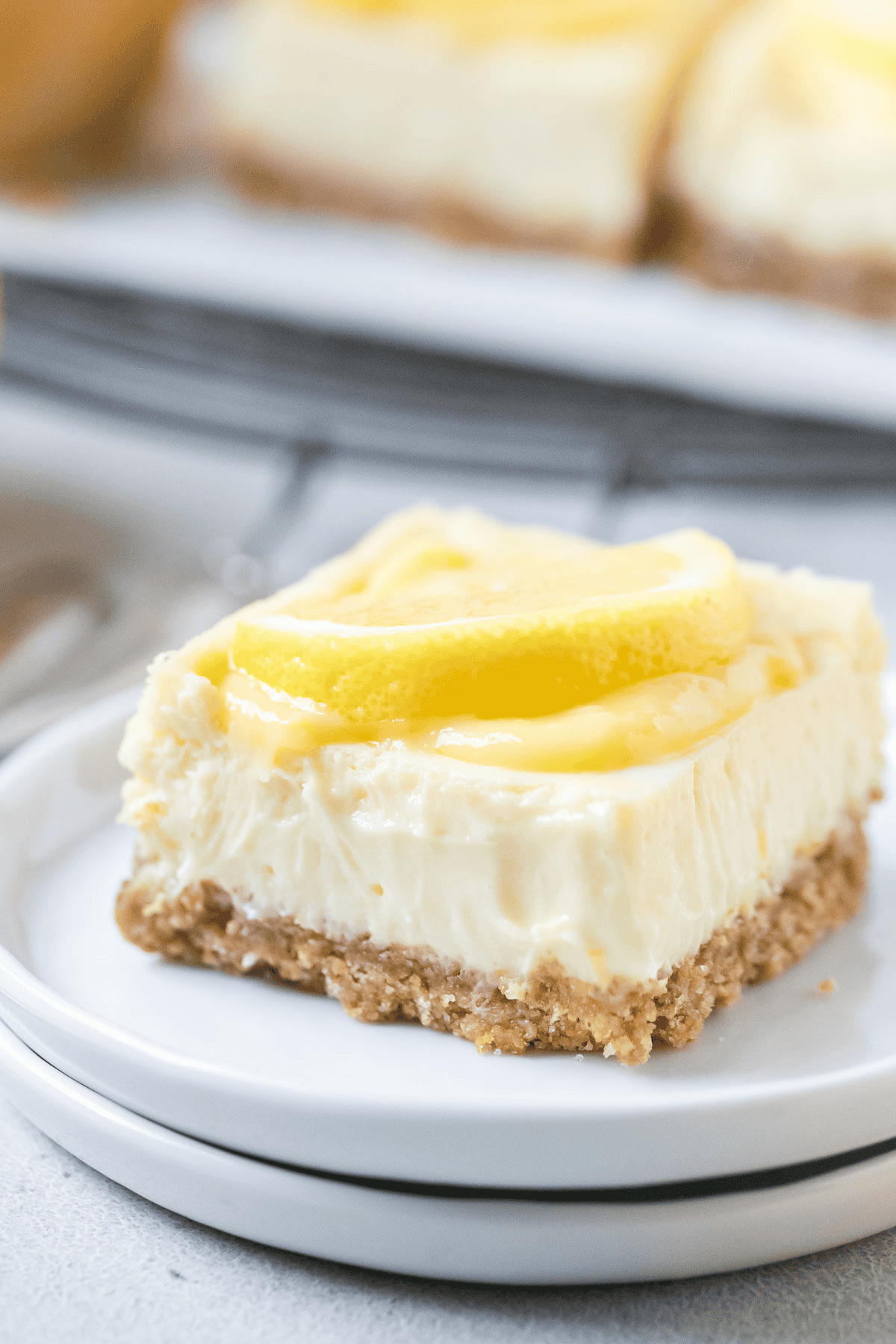 lemon cheesecake bar topped with lemon slice sitting on two small white plates