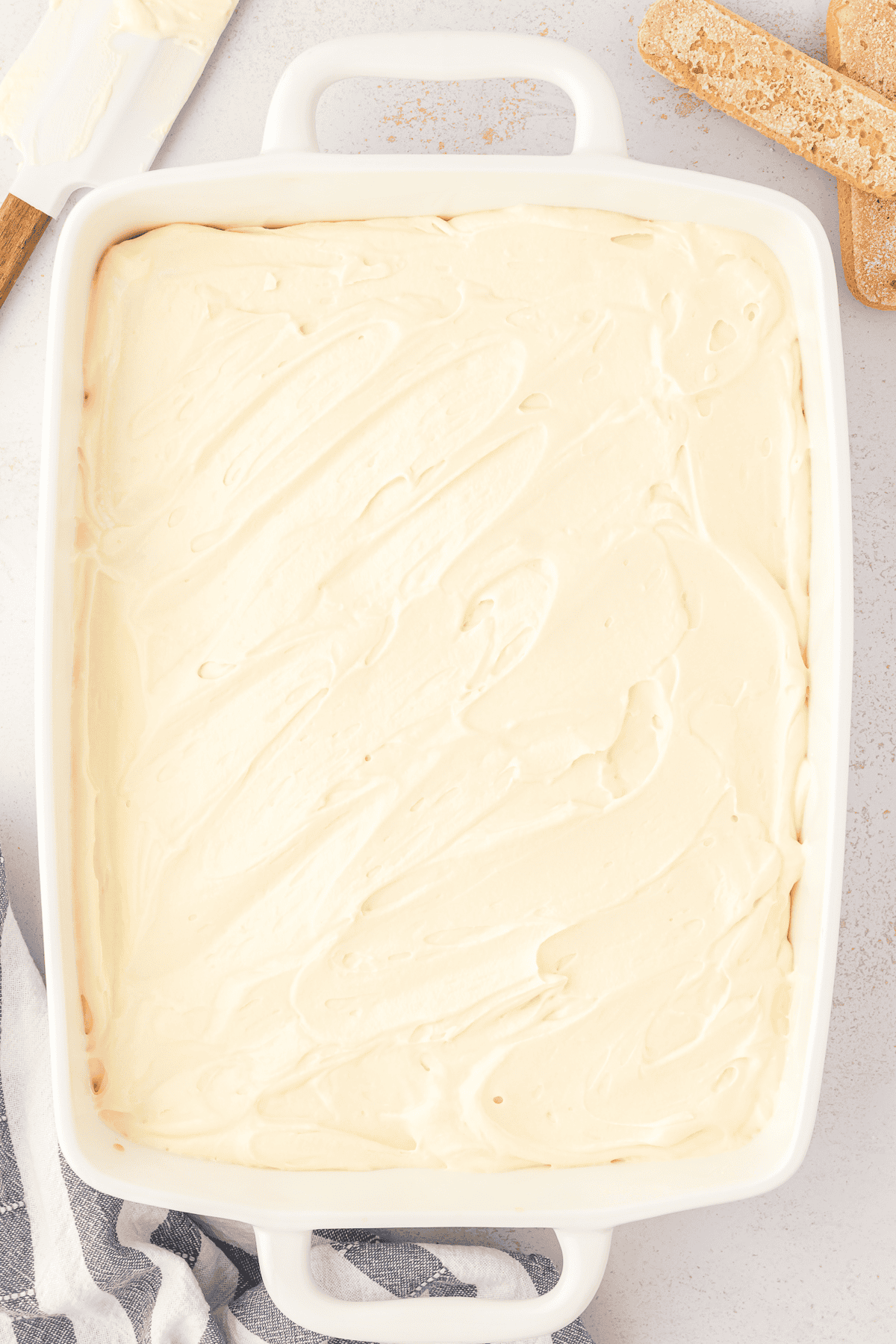 mascarpone mixture spread on top of ladyfingers in baking dish