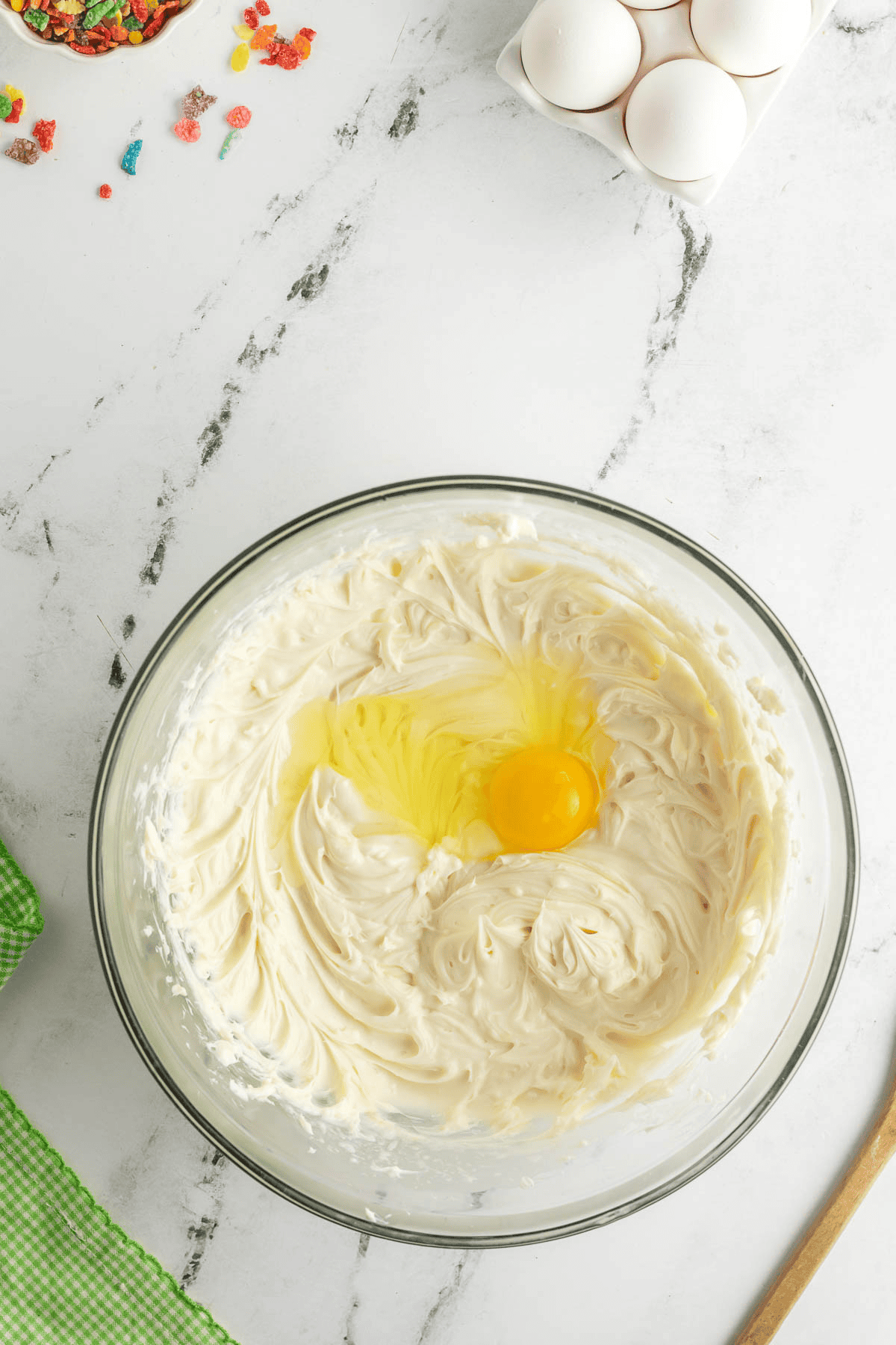 egg added to cheesecake batter in bowl