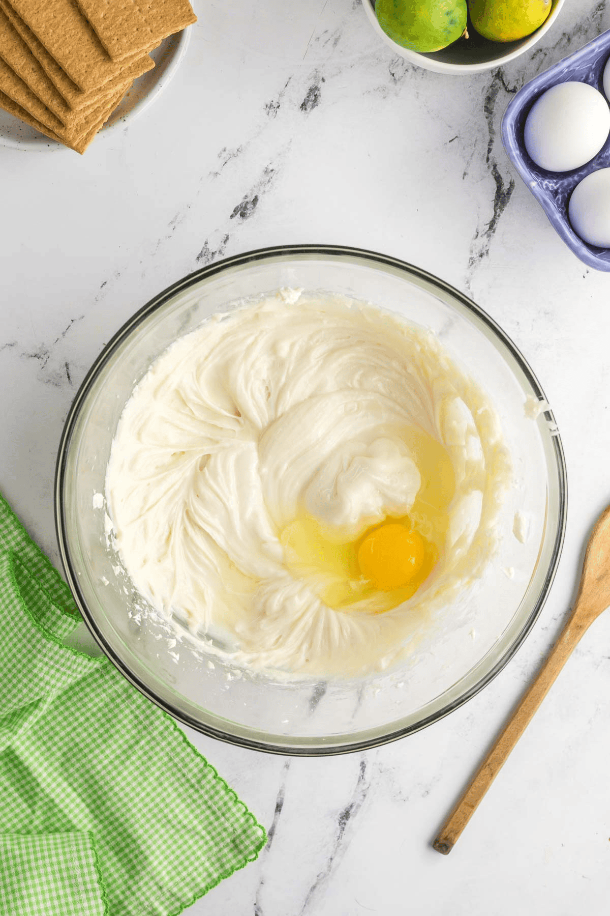 egg added to cheesecake batter in bowl