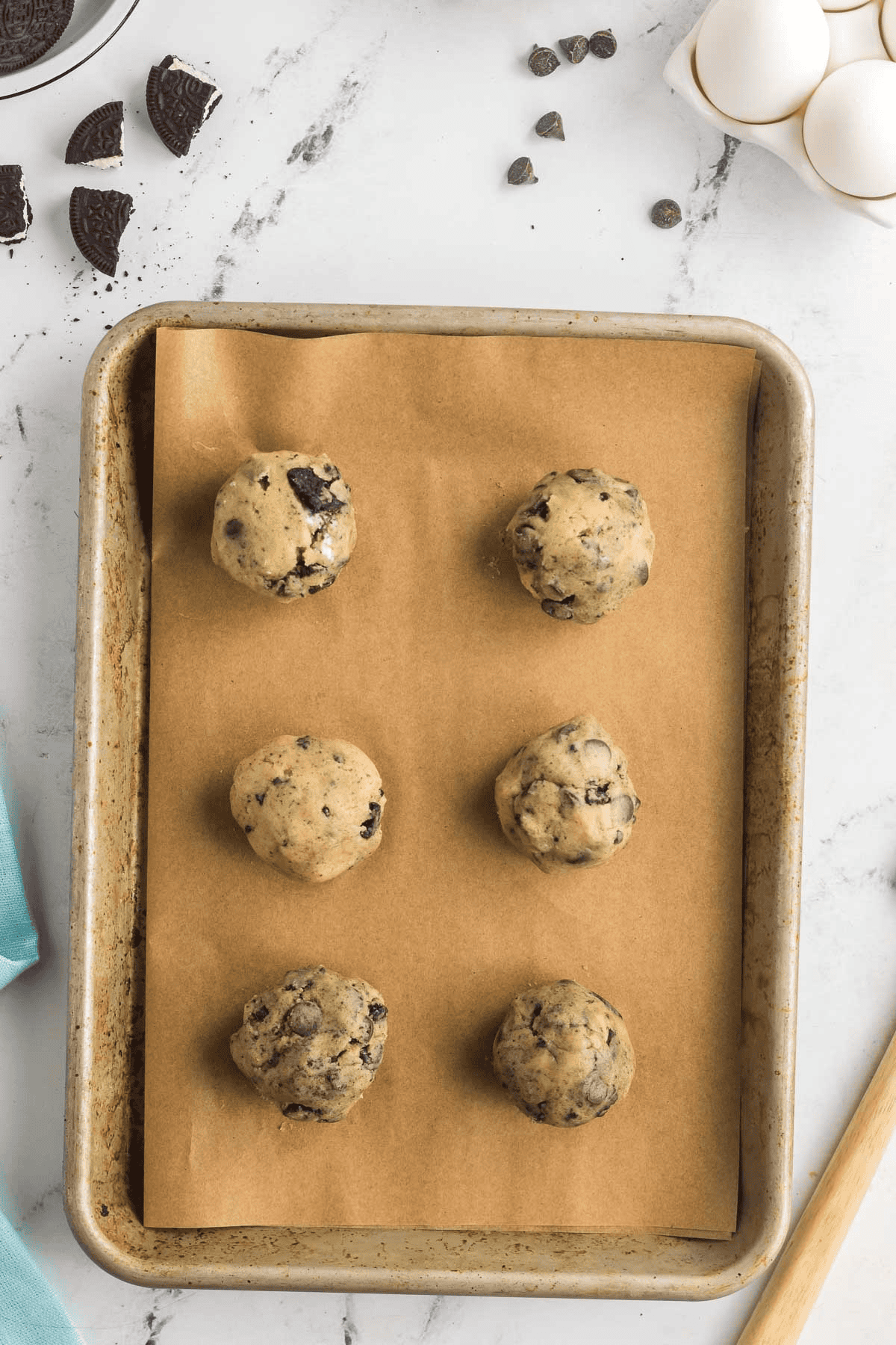 six unbaked oreo cheesecake cookies on cookie sheet