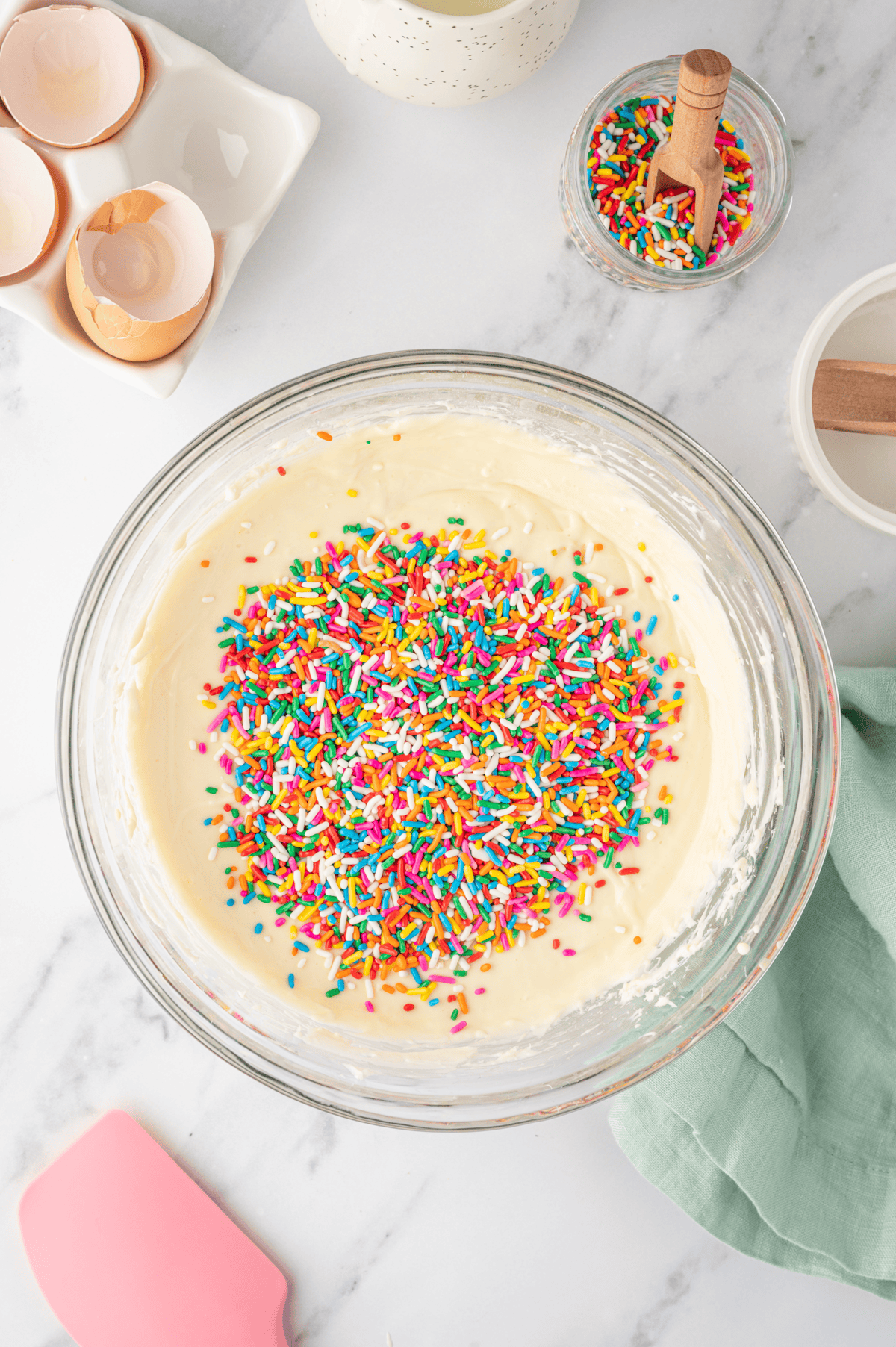 rainbow sprinkles added to bowl of cheesecake filling