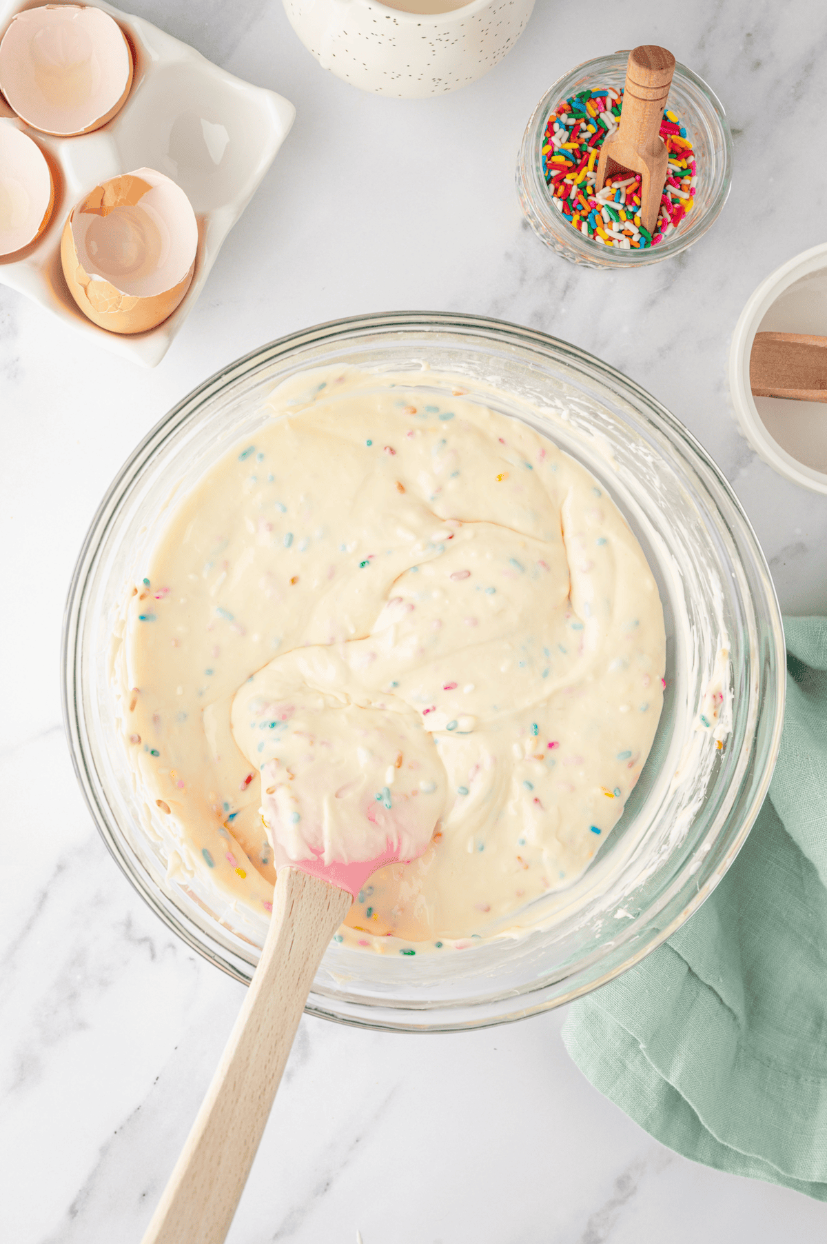 rainbow sprinkles folded into cheesecake filling with rubber spatula