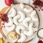 almond crescent cookies on a round wooden cutting board