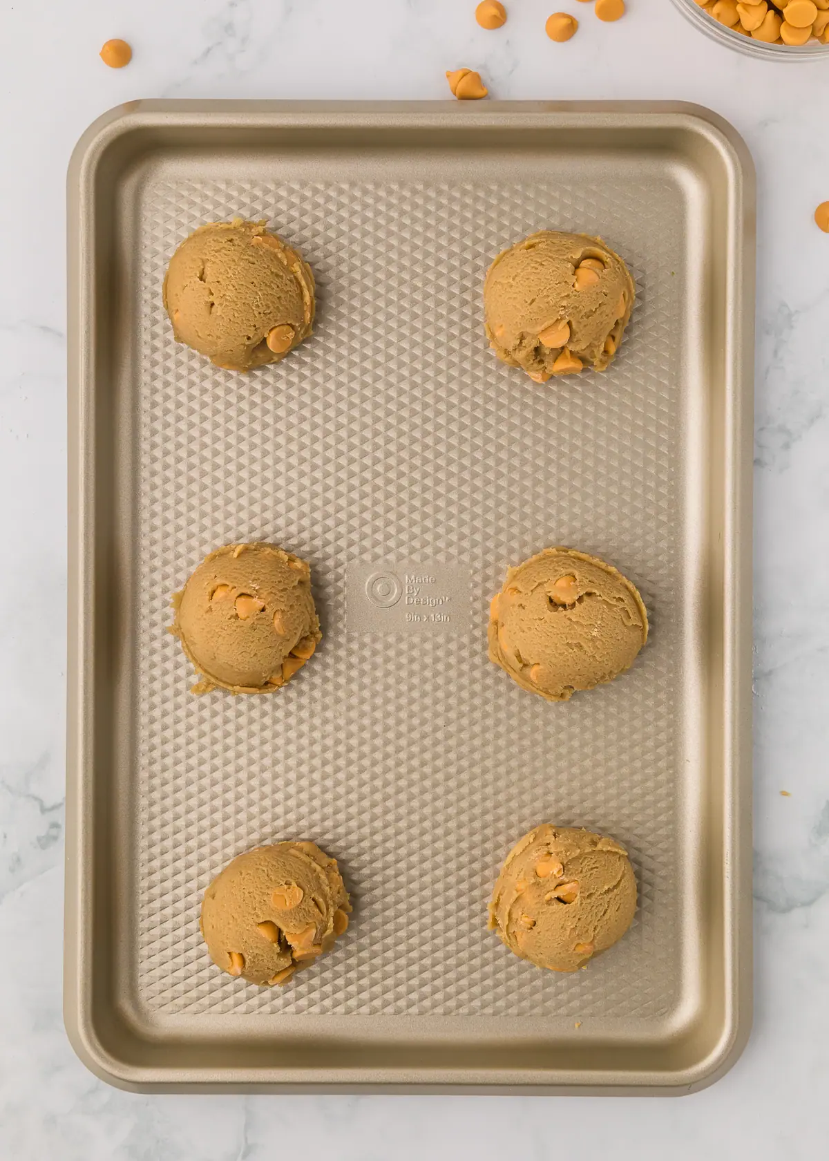 six unbaked butterscotch cookie dough balls on a baking sheet
