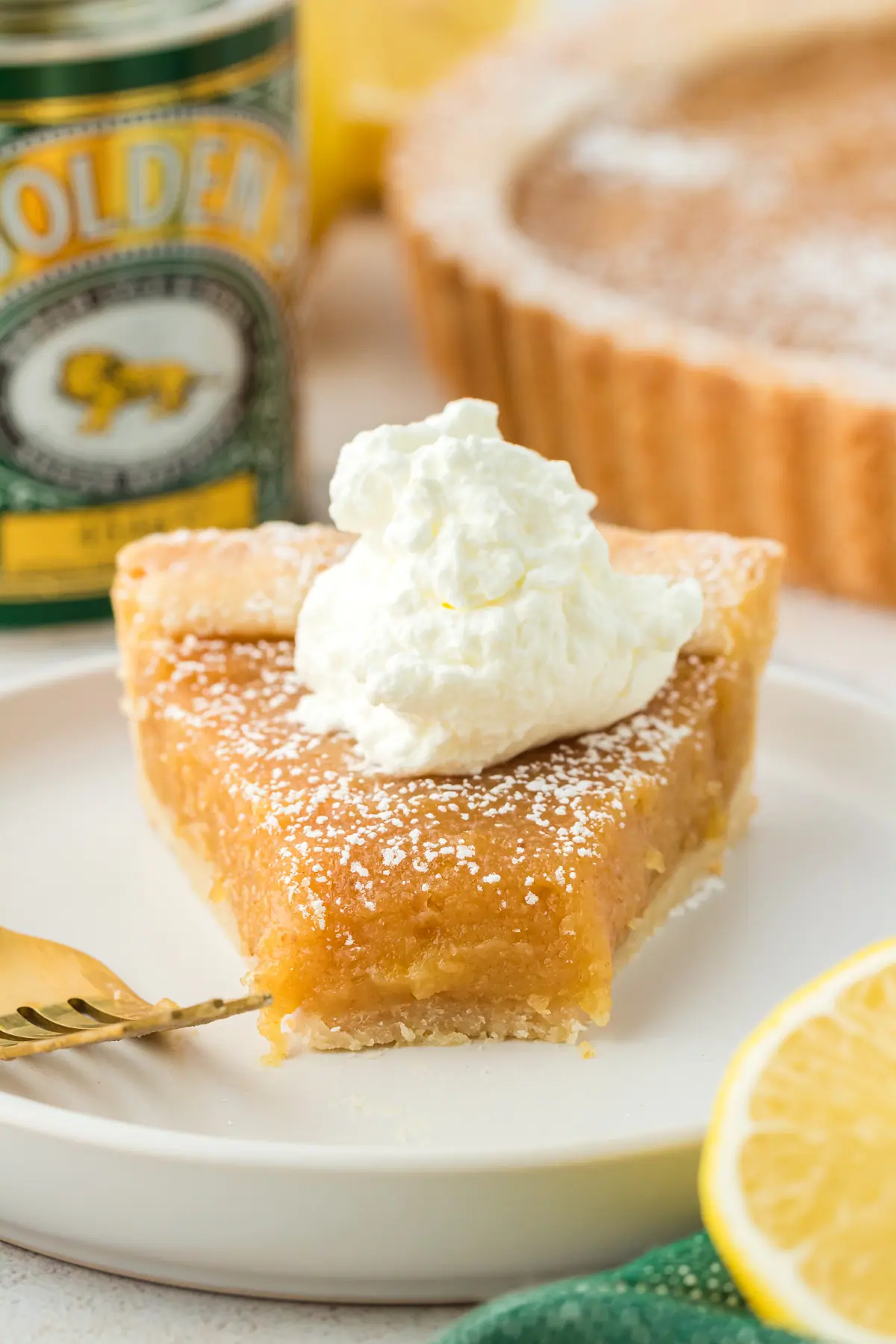 slice of treacle tart on a plate with a bite missing and topped with whipped cream