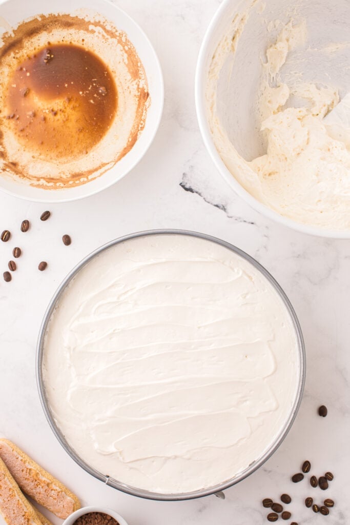 cheesecake batter spread on top of lady fingers