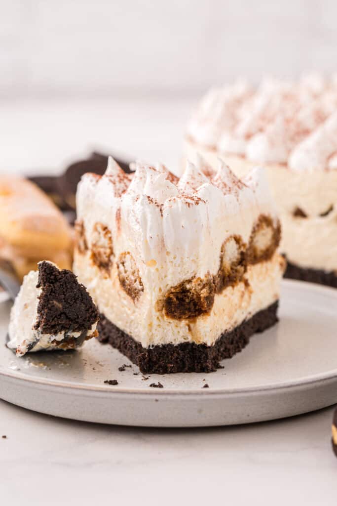 slice of tiramisu cheesecake with a forkful taken out of it on a plate