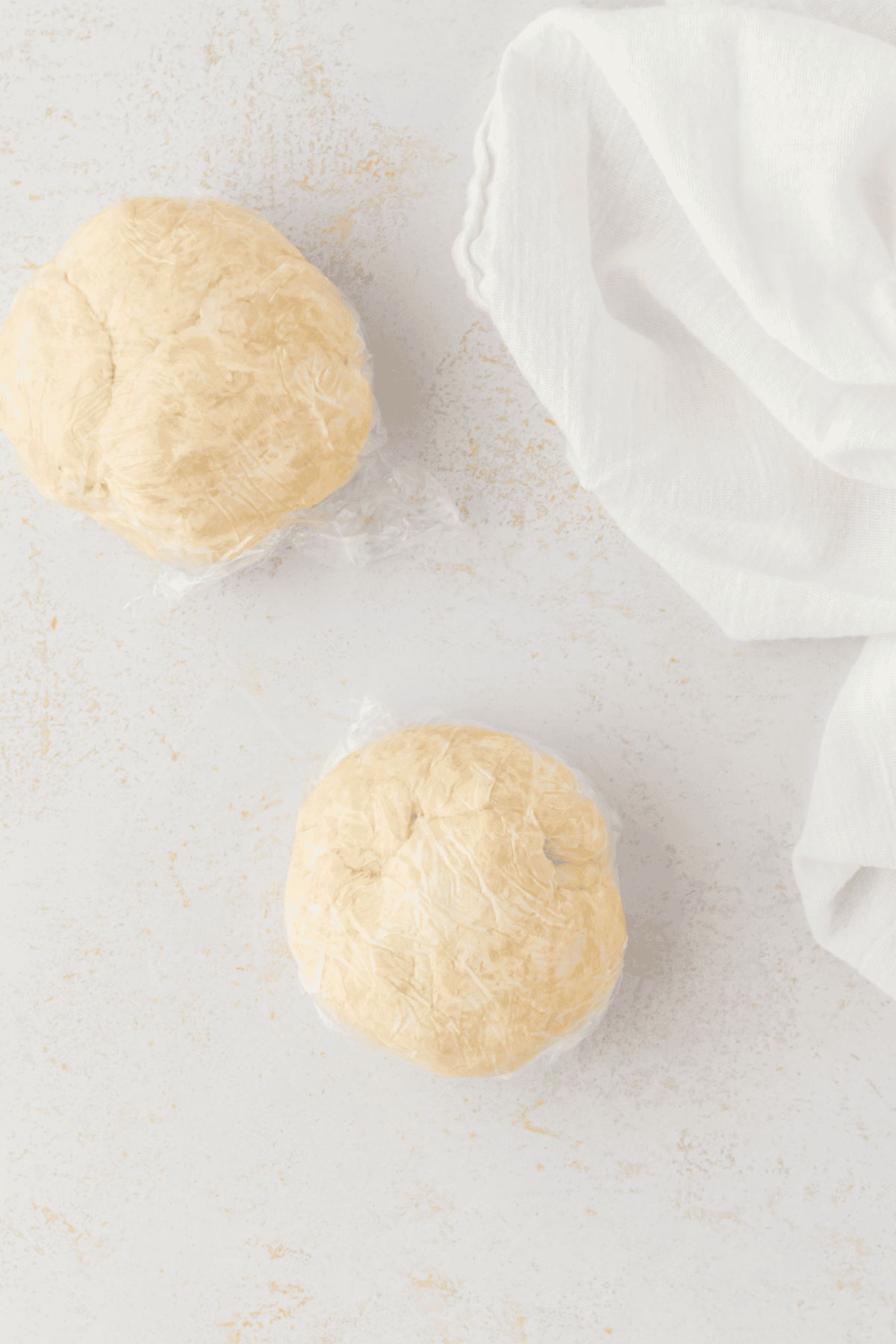 two balls of pie dough wrapped in plastic wrap