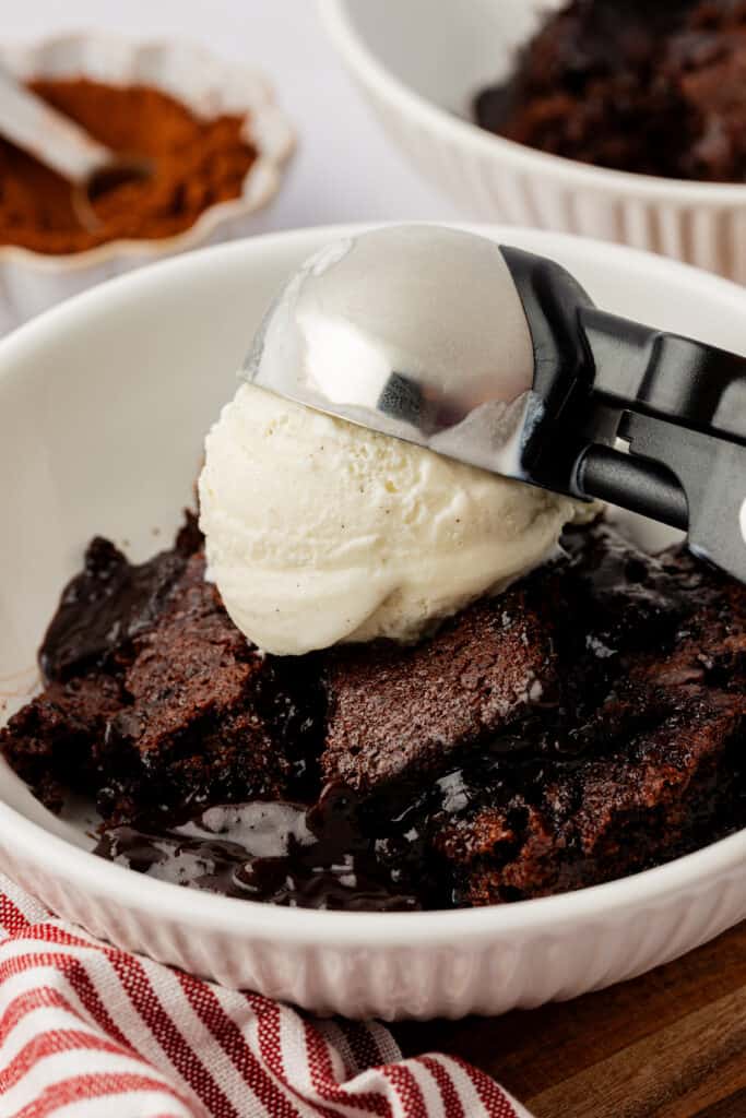 ice cream being scooped onto a bowl of chocolate cobbler