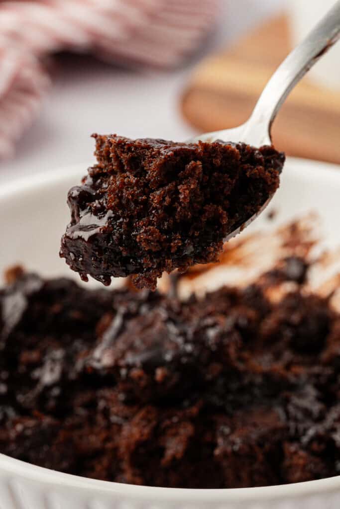 spoon lifting a bite of chocolate cobbler out of the bowl