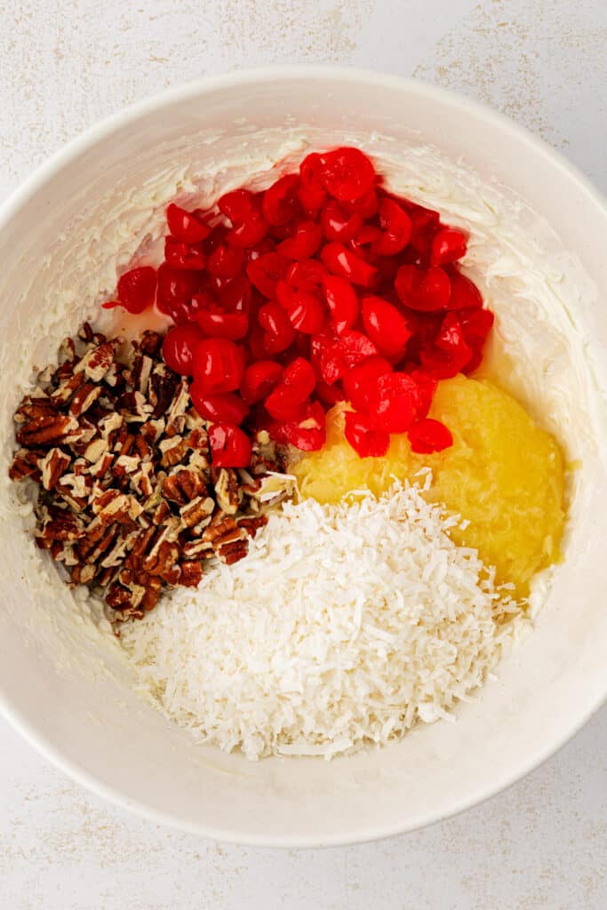 cherries, pineapples, pecans, and coconut added to cream cheese mixture in bowl