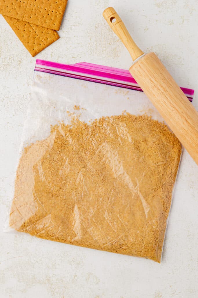 graham cracker crumbs in a plastic bag and a rolling pin