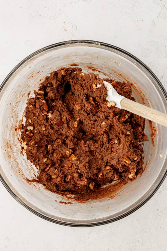 chocolate turtle cookie dough in a bowl with a spatula