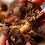 hand pulling a chocolate turtle cookie apart