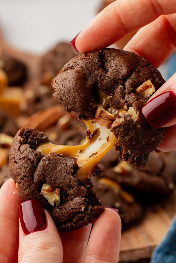 hand pulling a chocolate turtle cookie apart