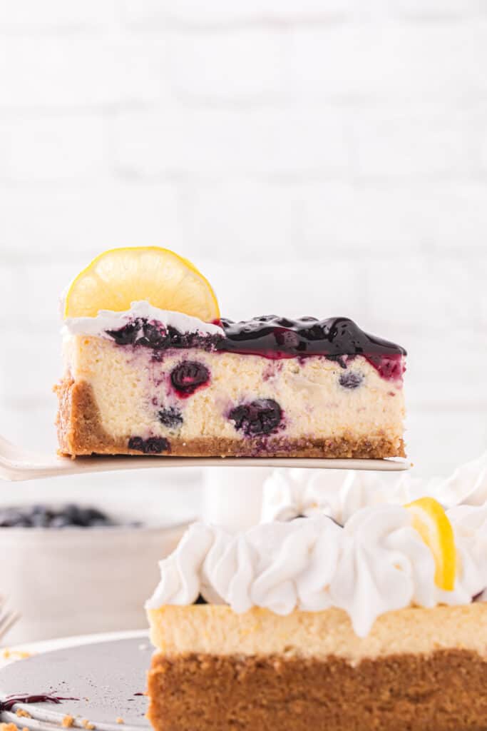 cake server serving a slice of the lemon blueberry cheesecake