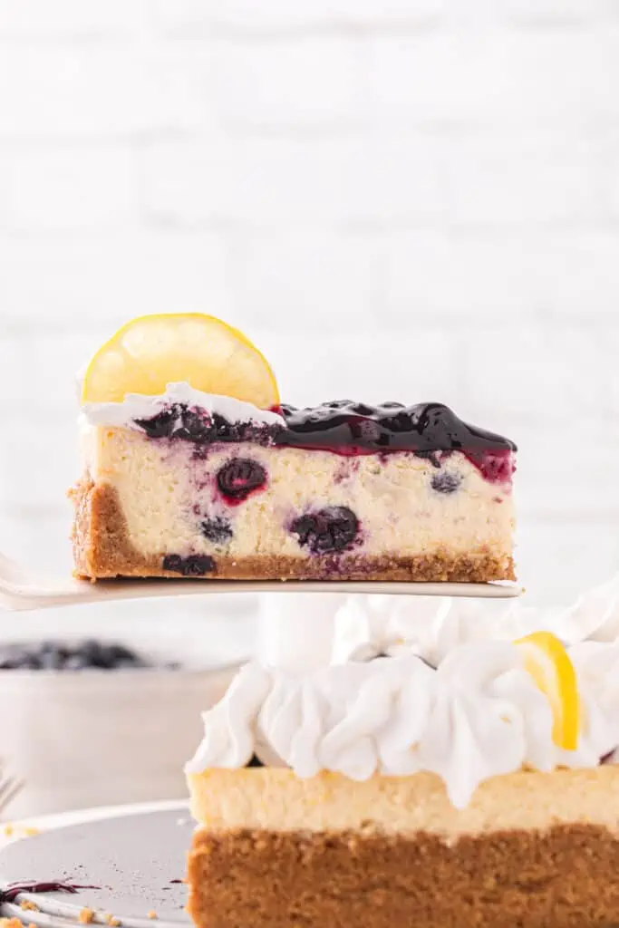 cake server serving a slice of the lemon blueberry cheesecake