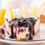 slice of lemon blueberry cheesecake on a plate with a bite missing