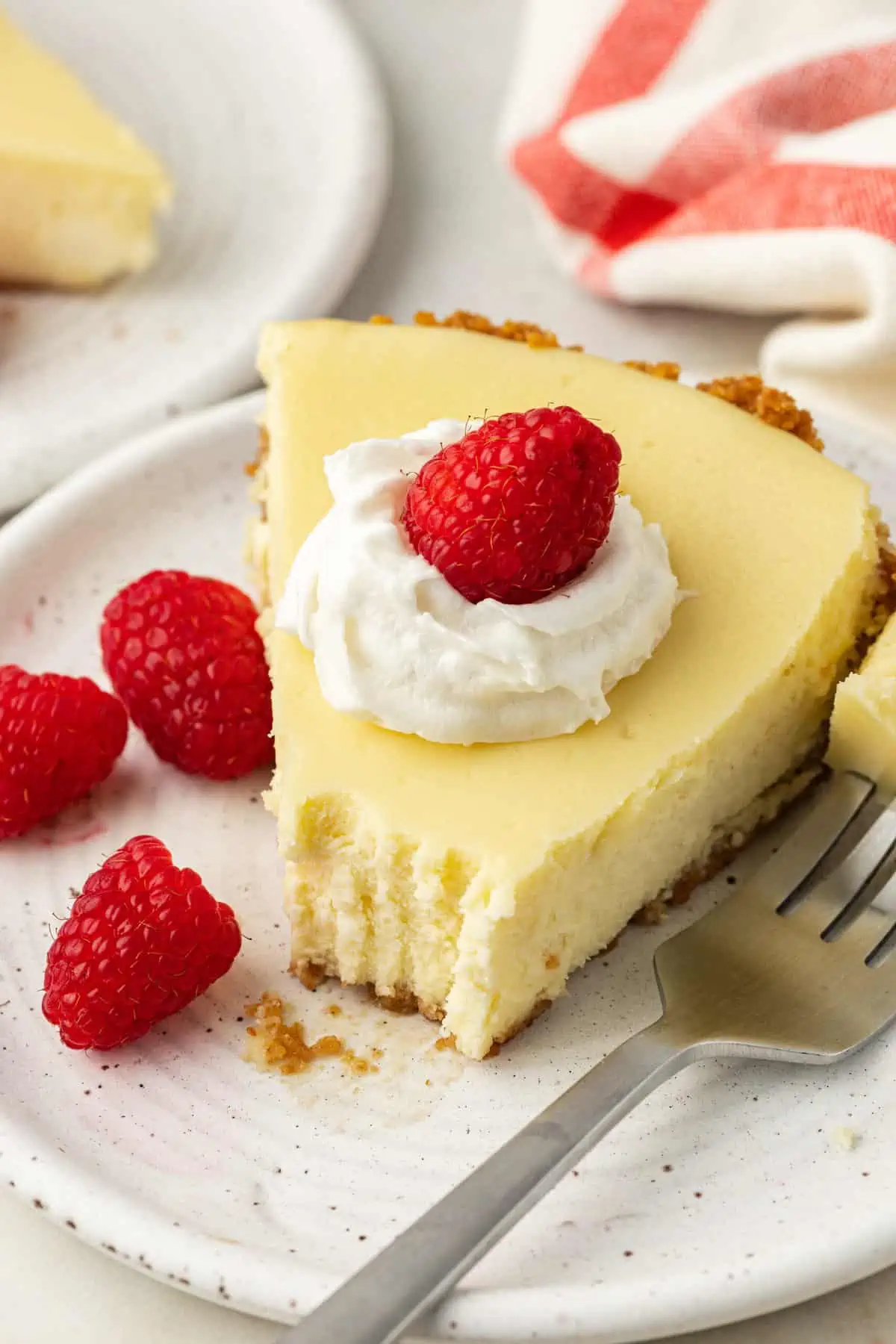 slice of cheesecake pie on a plate topped with whipped cream and raspberries