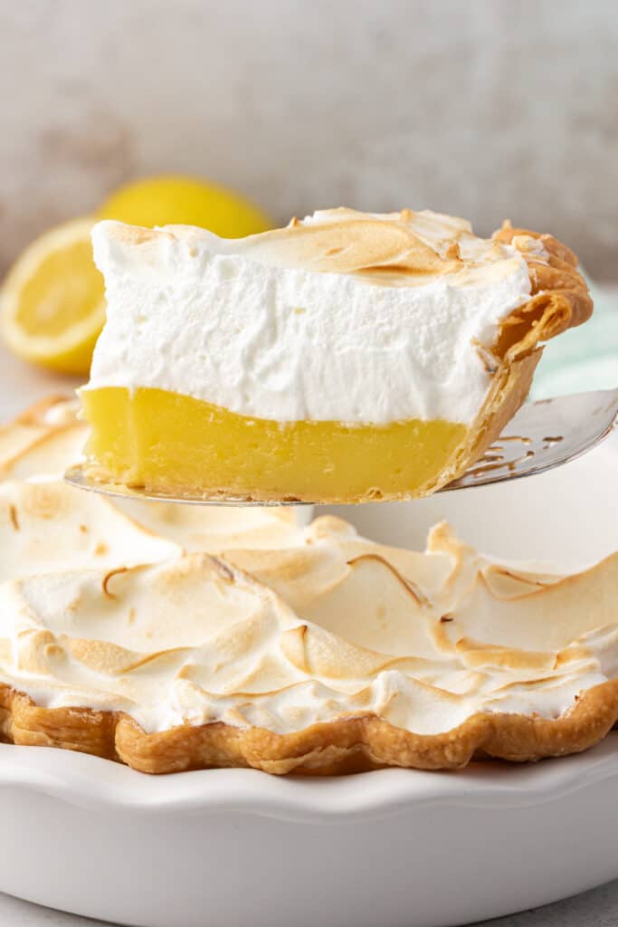 spatula removing a slice of lemon meringue pie from the whole pie