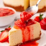 strawberry topping spooned onto a slice of cheesecake