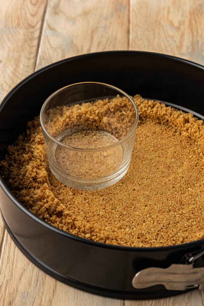 graham cracker crust press down into springform pan with a drinking glass