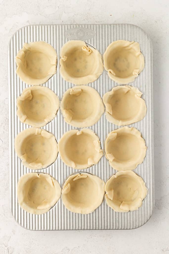 muffin tin filled with small circles of pie crust in each well.