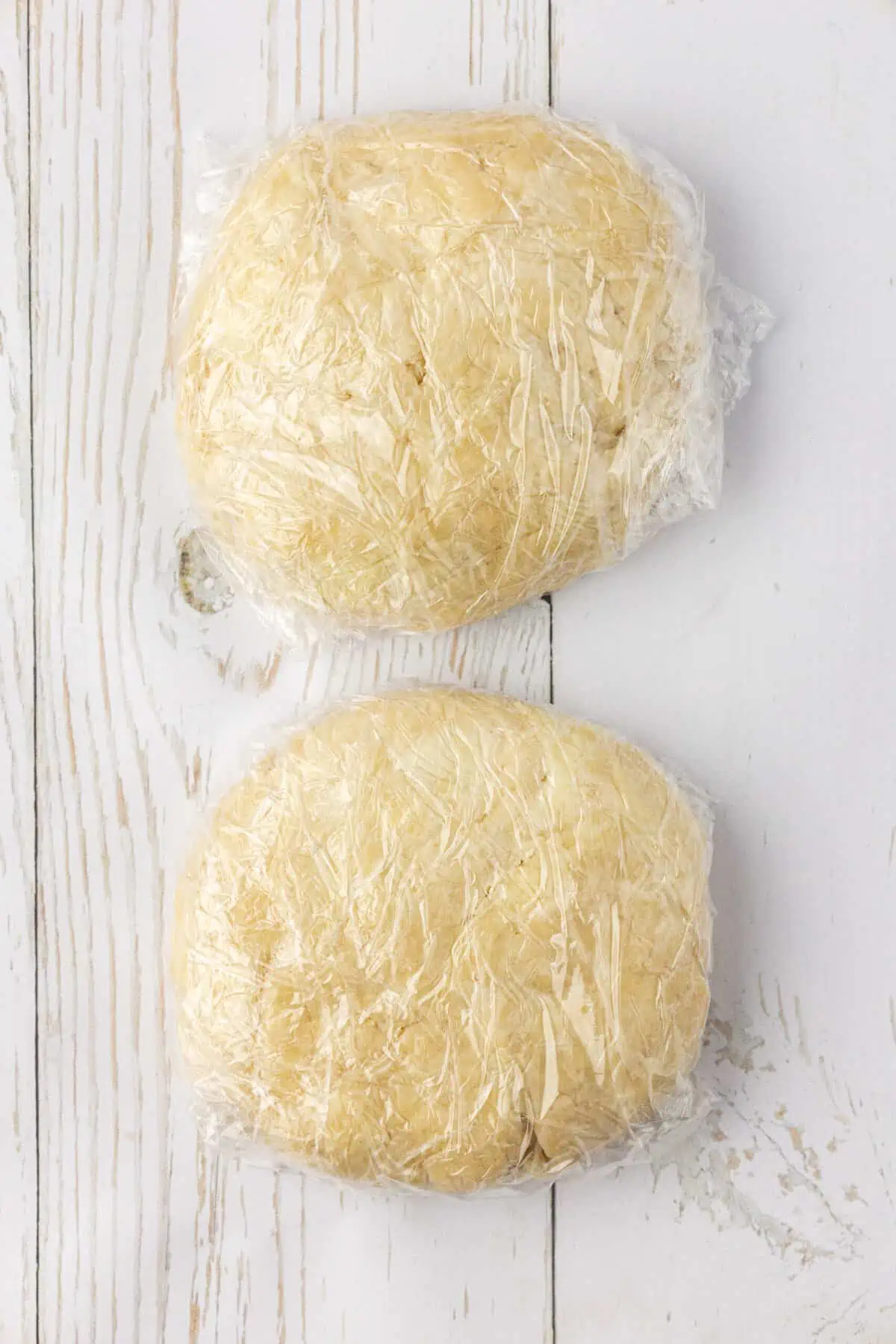 pie dough divided into two portions and wrapped in plastic wrap