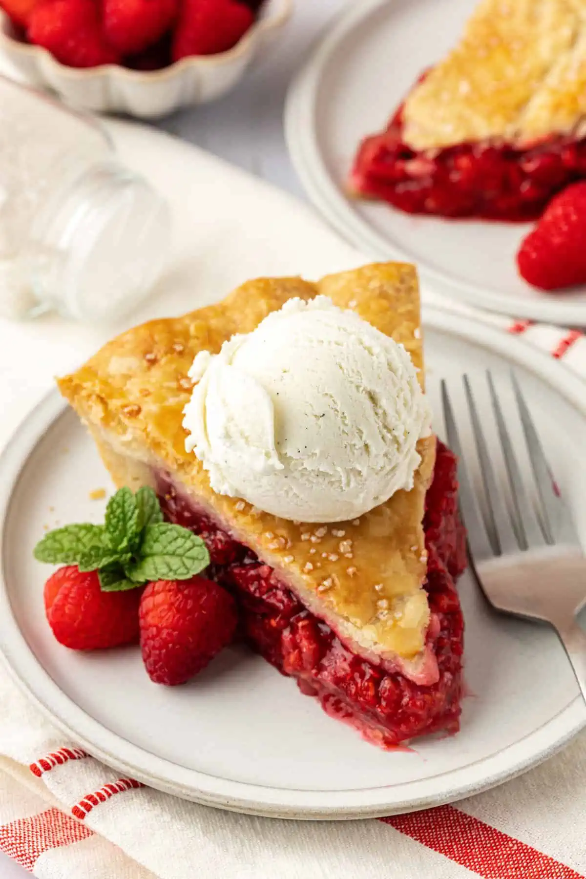 slice of raspberry pie topped with scoop of vanilla ice cream
