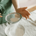 flour being sifted into a bowl