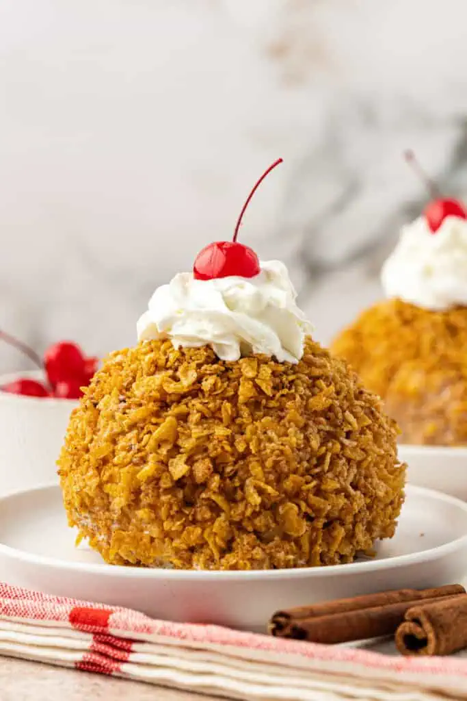 mexican fried ice cream on a plate topped with whipped cream and a cherry
