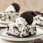 no bake oreo cheesecake bar on a plate topped with whipped a whole oreo cookies