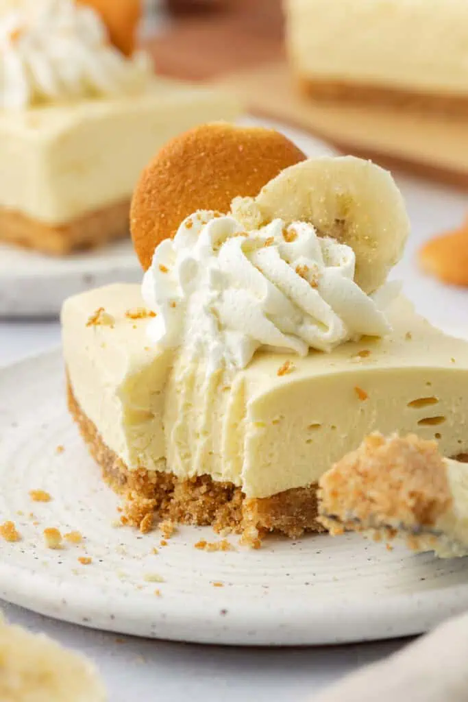 banana pudding cheesecake bar on a plate with a forkful missing