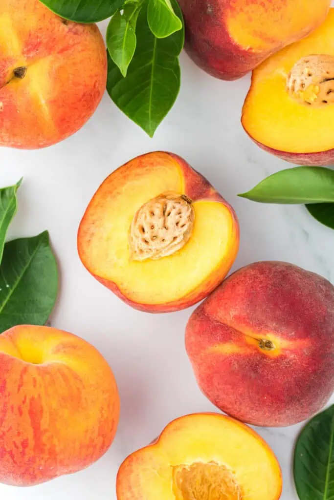 a bunch of fresh peaches, with one peach cut in half