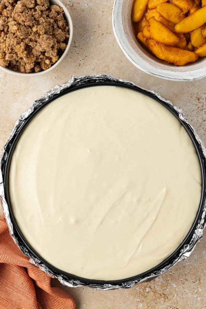 unbaked peach crumble cheesecake in pan
