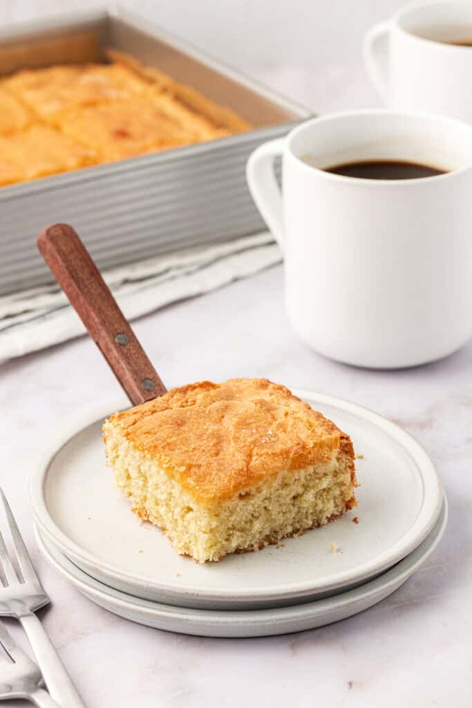 slice of cake on a plate with a cup of coffee
