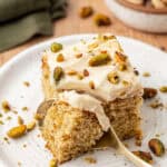 slice of pistachio cake with a spoon slicing into it