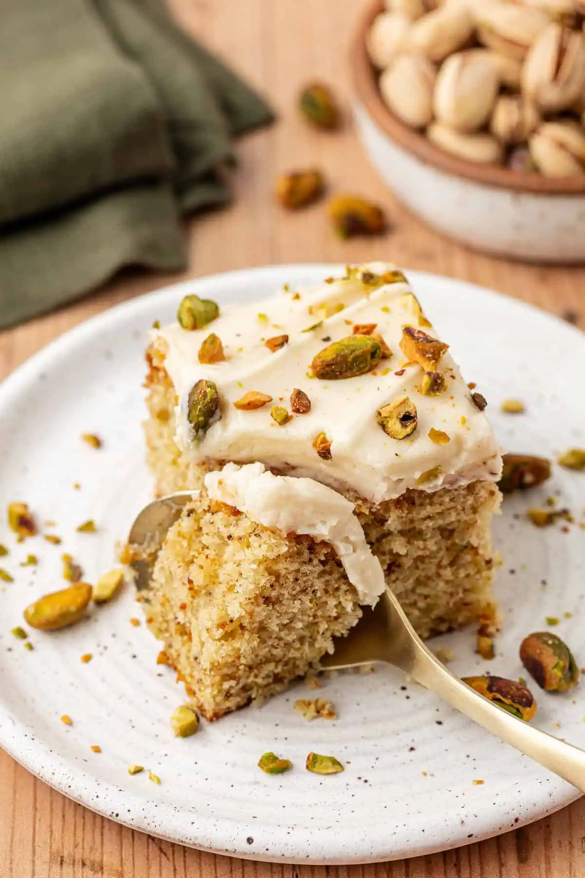 slice of pistachio cake with a spoon slicing into it