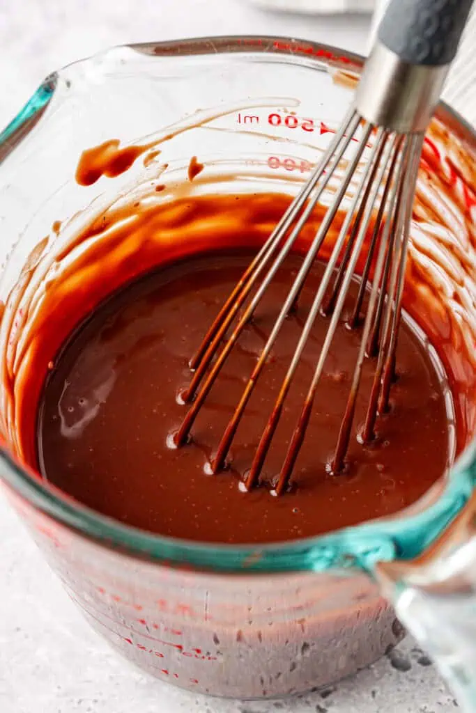 ganache in a measuring cup with a whisk