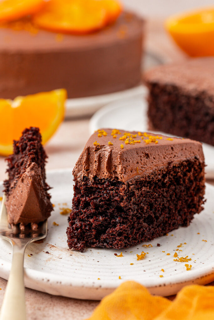 slice of chocolate orange cake on a plat with a forkful missing