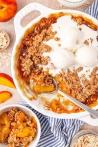 dish of peach crisp topped with vanilla ice cream