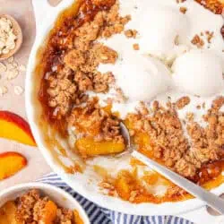 dish of peach crisp topped with vanilla ice cream
