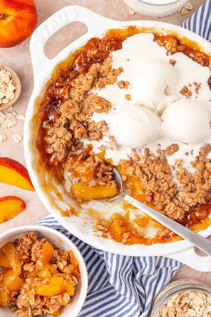 dish of peach crisp topped with vanilla ice cream