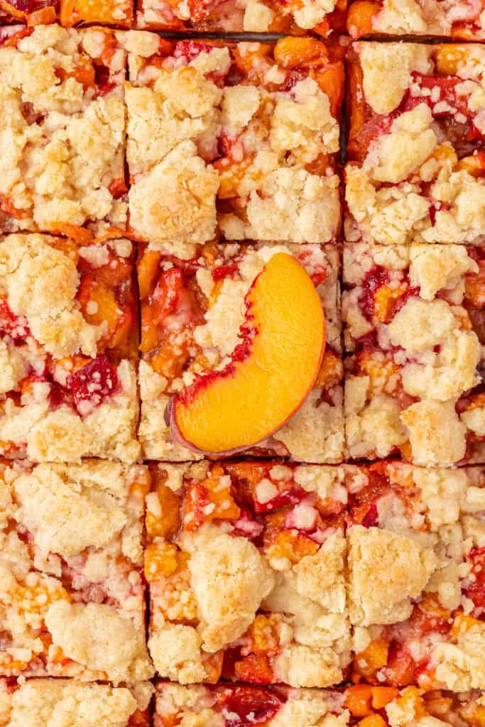 peach crumble bars cut with a slice of peach on top