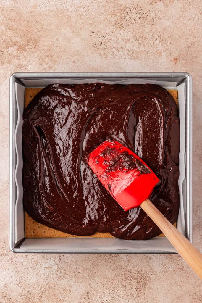 brownie batter spread on top of graham crackers in pan