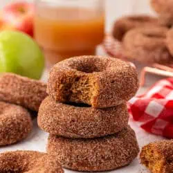 three apple cider donuts stacked on top of each other with the top donut having a bite taken out of it